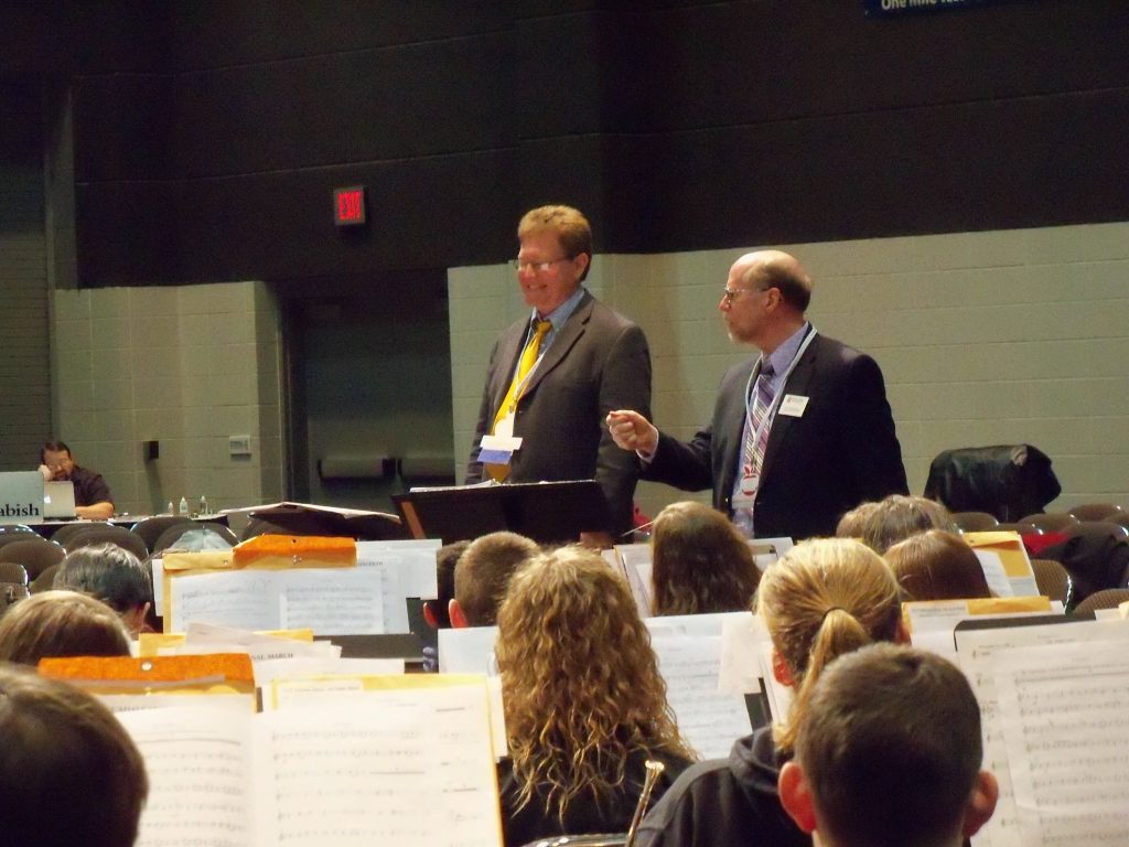 Rehearsal photo of composer Jesse Ayers with conductor Jeffrey Scott Doebler and the 2014 Indiana Junior All-State Band